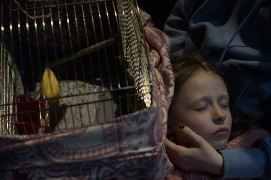 Kadr z filmu "Border". Dziewczynka śpi na kolanach swojej starszej siostry. Obok niej klatka z kanarkiem.